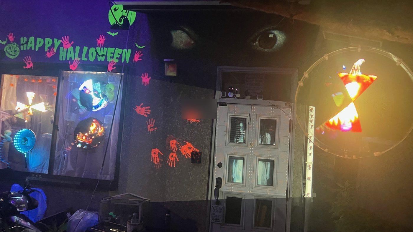 ハロウィンの玄関。ドアの窓とその上の壁にプロジェクションマッピング、左の窓と右に3DホログラムLEDファン、壁にHAPPY HALLOWEENの文字