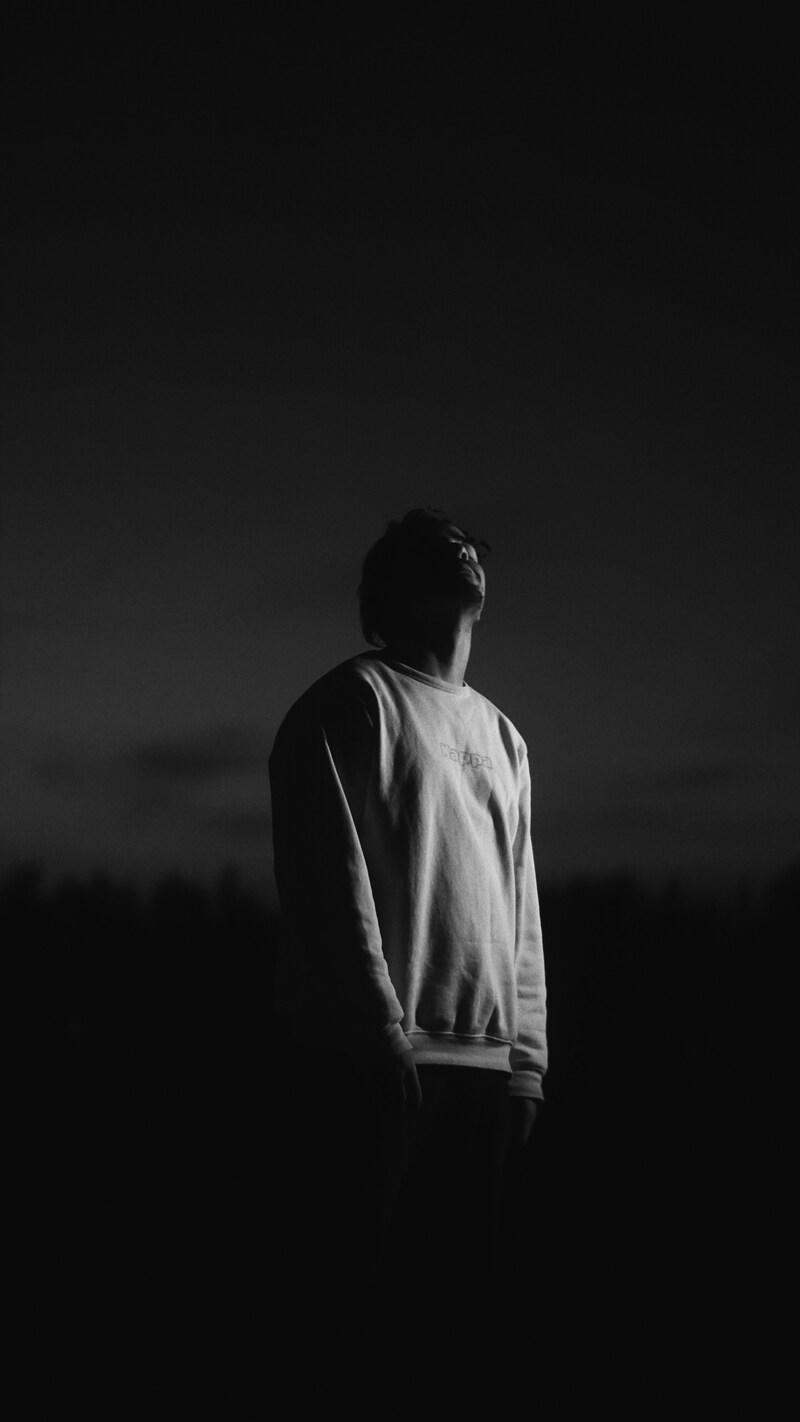 暗闇の中で空を見上げるミドル世代の男性のシルエット