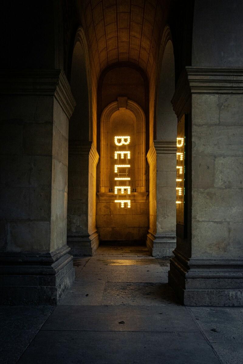 暗いアーチの先に光るBELIEFの文字